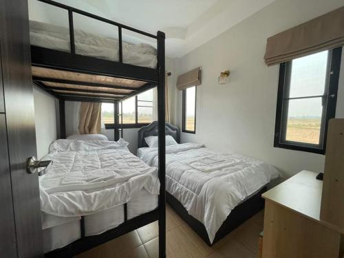 a bedroom with two bunk beds and a window at บ้านกลางนาพูลวิลล่า in Nan