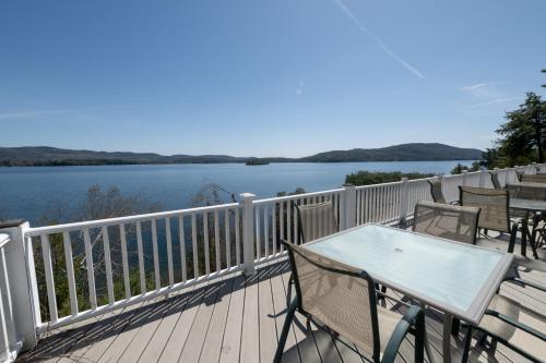 a table and chairs on a deck with a view of a lake at Depe Dene Lakeside Resort in Lake George
