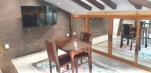 mesa de madera con sillas y TV en la pared en Lux Central Shumen Apartment en Shumen