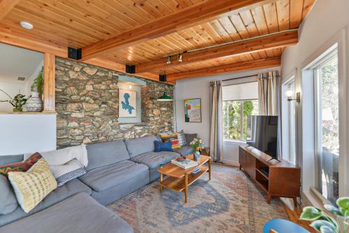 a living room with a blue couch and a stone wall at Huvila Haven Lake Front Home with Dock and Hot Tub in Newman Lake