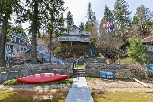 a house with a flag and a boat in the water at Huvila Haven Lake Front Home with Dock and Hot Tub in Newman Lake
