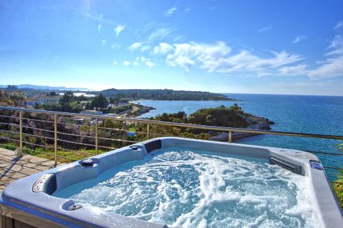 a hot tub on a balcony overlooking the ocean at Beachfront Villa Seasun by PosarelliVillas in Agios Spyridon Corfu
