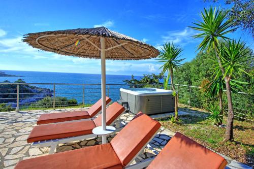 a patio with two chairs and an umbrella at Beachfront Villa Seasun by PosarelliVillas in Agios Spyridon Corfu