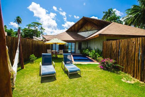 a backyard with two chairs and an umbrella at Pousada Rangai in Maragogi