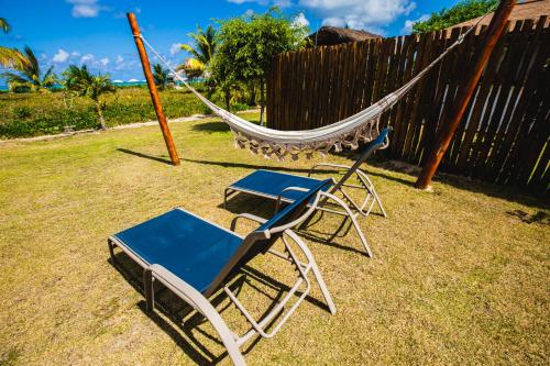two chairs and a hammock in a yard at Pousada Rangai in Maragogi