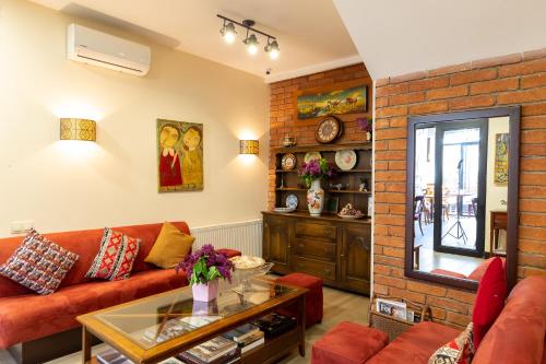 a living room with a red couch and a brick wall at Elea Old Tbilisi Hotel in Tbilisi City