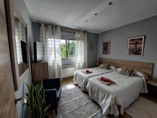 een slaapkamer met 2 bedden, een tv en een raam bij Casa playa La Solana en Nigran in Nigrán