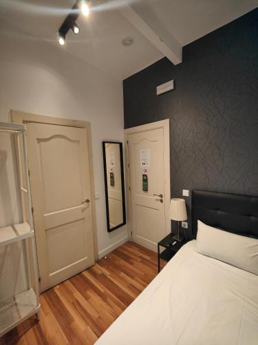1 dormitorio con cama blanca y pared negra en SINGLE ROOMS en Madrid