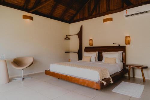 a bedroom with a large bed and a chair at Pousada Rangai in Maragogi