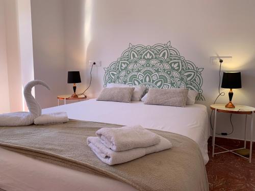 una camera da letto con un grande letto bianco con asciugamani di Doranda Rooms Las Canteras a Las Palmas de Gran Canaria