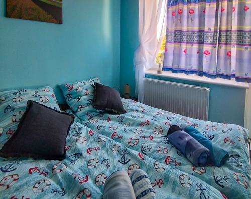 a bed with a blue comforter and two pillows at Kolorowa Chata in Ustronie Morskie