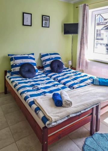 Cama grande con sábanas y almohadas azules y blancas en Kolorowa Chata, en Ustronie Morskie