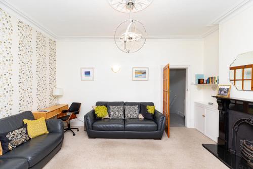a living room with a black leather couch at Pier Top - Free all Island parking permit in Ventnor