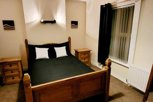 a bedroom with a bed with a green comforter and a window at Tods Lodge - Quiet area in Derry City in Derry Londonderry