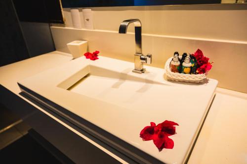 a bathroom sink with a faucet and a basket of figurines at Pousada Rangai in Maragogi