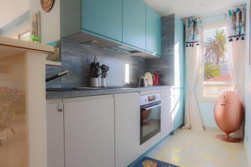 une cuisine avec des placards blancs et un bleu dans l'établissement CROISETTE AZUR ONE BEDROOM APARTMENT WITH TERRACE, à Cannes