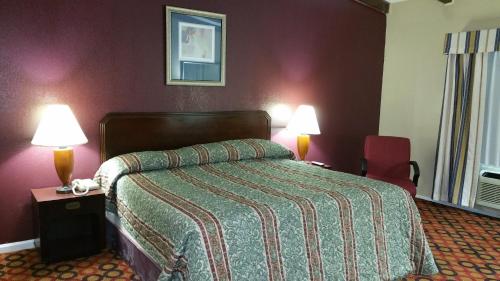 a hotel room with a bed and two lamps at Executive Inn and Suites Waxahachie in Waxahachie