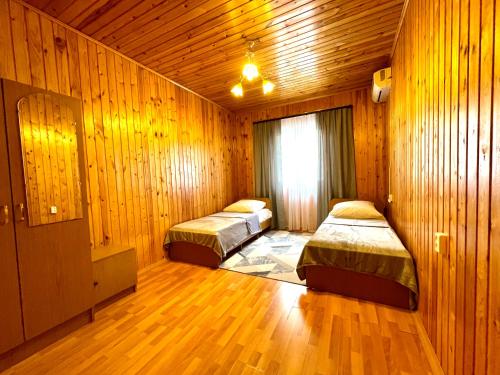 2 Betten in einem Zimmer mit Holzwänden und Holzböden in der Unterkunft Дом под ключ Комфортик in Gagra