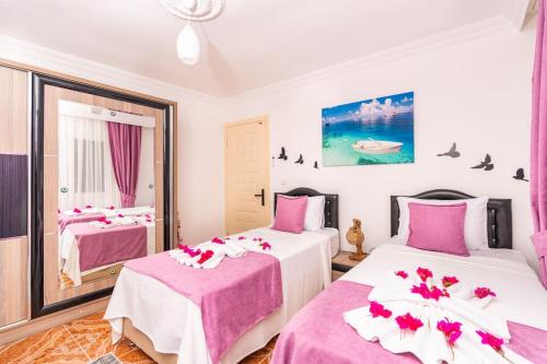 two beds in a room with pink and white at Nefesim suit apart kaş kalkan in Kalkan