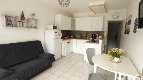 Il dispose d'une cuisine et d'un salon avec un canapé et une table. dans l'établissement Rez de jardin à 100m de la mer, à Cavalaire-sur-Mer