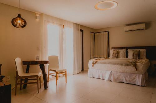 a bedroom with a bed and a table and chairs at Pousada Rangai in Maragogi