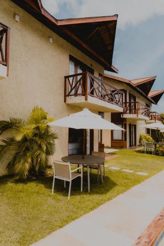 a table with an umbrella in front of a house at Pousada Rangai in Maragogi