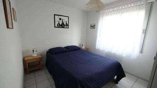 une chambre avec un lit bleu et une fenêtre dans l'établissement Rez de jardin à 100m de la mer, à Cavalaire-sur-Mer