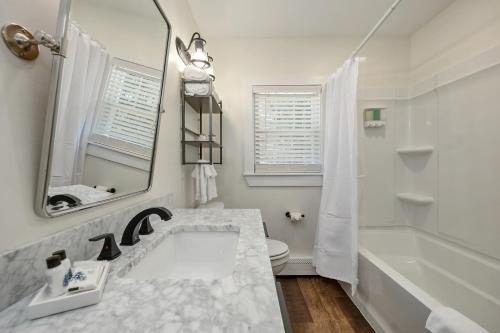a white bathroom with a sink and a tub and a mirror at The Inn & More in Bartlett