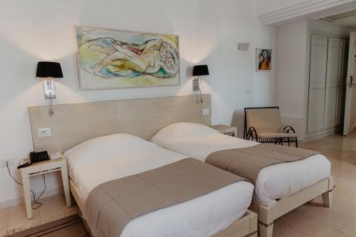 塔格梅斯的住宿－Hotel Bougainvillier Djerba，酒店客房设有两张床,墙上挂有绘画作品