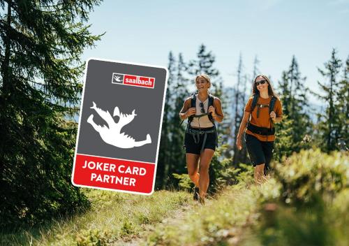 two women walking on a trail next to a sign at Hotel VIEW - incl Joker Card in Summer in Saalbach Hinterglemm