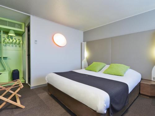 a bedroom with a large bed with green pillows at Campanile Chambéry in Chambéry