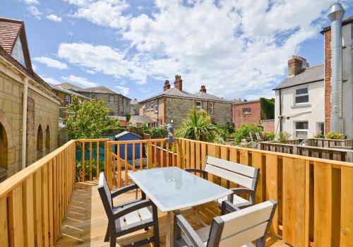 a wooden balcony with a white table and chairs at Pier Top - Free all Island parking permit in Ventnor