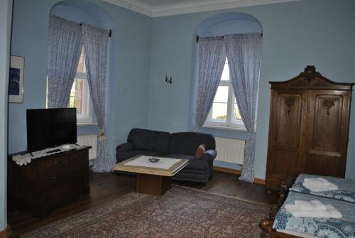 a living room with a couch and a tv and two windows at Schloss Triestewitz in Arzberg