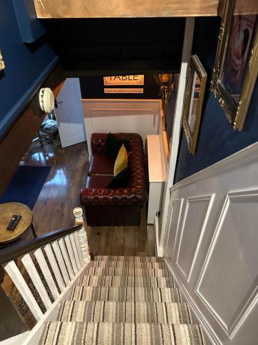 a living room with a couch and a staircase at 8 Opera Suites, Llangollen in Llangollen