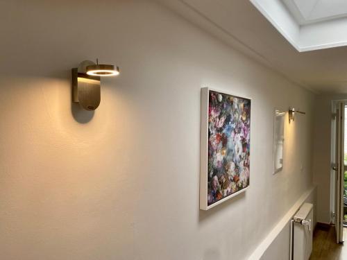 a painting hanging on a wall with a light on it at Köln City Apartments in Cologne
