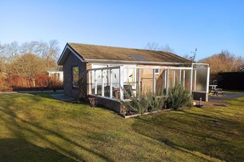 a small house with large windows on a yard at Vakantiehuis Hollum Ameland dichtbij strand en met ruime tuin - Ameland39 nl in Hollum