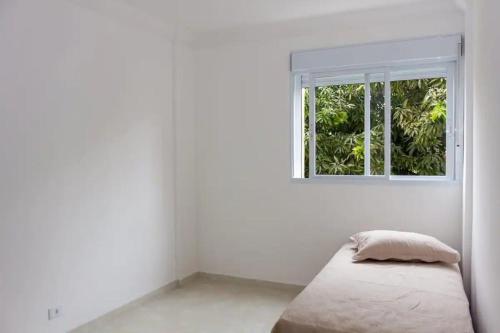een witte kamer met een bed en een raam bij Apê 2 in Sao Paulo