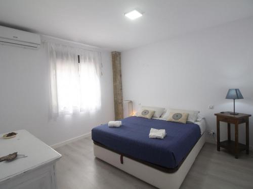 a bedroom with a bed with blue sheets and a window at Lightbooking Ancora Cádiz in El Puerto de Santa María