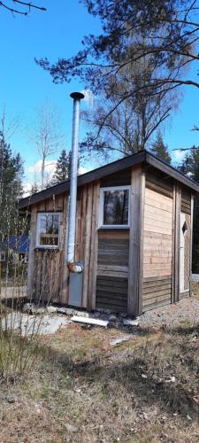 a small wooden house with a chimney on it at Rosa's stuga in Tasebo