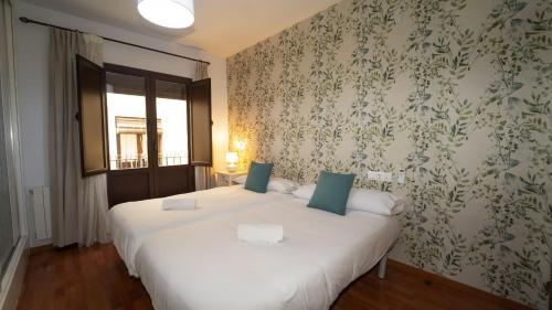 a bedroom with two beds and a wall with floral wallpaper at Lightbooking El Realejo Granada in Granada