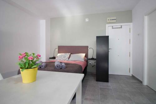 a living room with a bed and a table with flowers at Lightbooking Estadio Cádiz in Cádiz