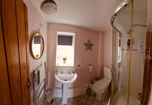 a bathroom with a sink and a toilet and a window at Hideaway Cottage Sleaford in Sleaford