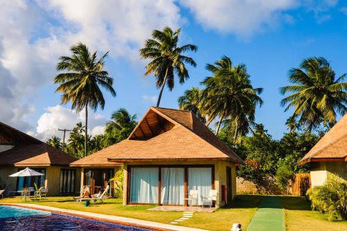 a resort with a swimming pool and palm trees at Pousada Rangai in Maragogi