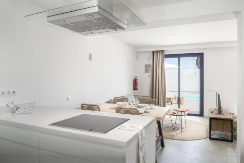 een witte keuken met een tafel en een woonkamer bij Lightbooking Edem Playa del Hombre in Telde