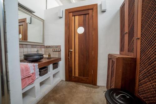 La salle de bains est pourvue d'un lavabo et d'une porte en bois. dans l'établissement Lightbooking Haría Lanzarote, à Haría