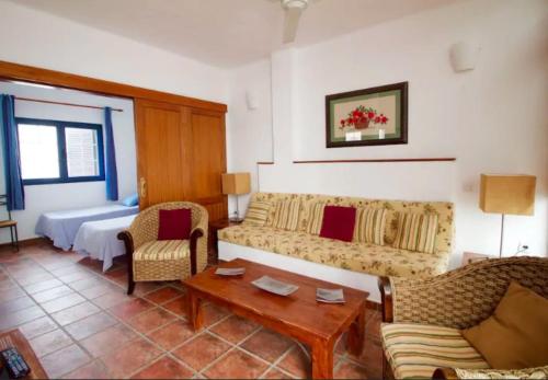 een woonkamer met een bank, stoelen en een tafel bij Lightbooking La Graciosa in Caleta de Sebo