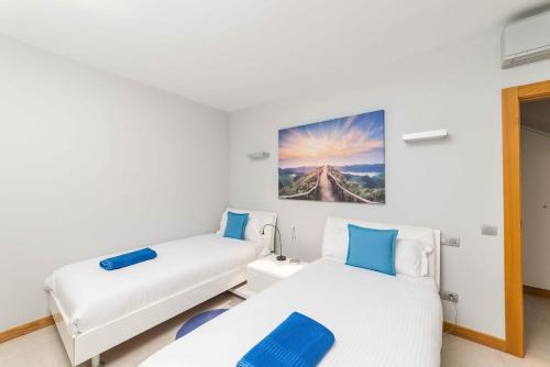 2 camas en una habitación blanca con detalles azules en Lightbooking piscina privada Salobre Golf, en San Bartolomé