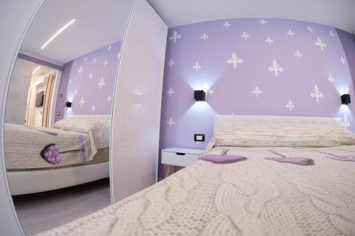 Schlafzimmer mit einem Bett mit lila Wänden und einem Spiegel in der Unterkunft Appartamento Vale Mare Vista Canale in Chioggia