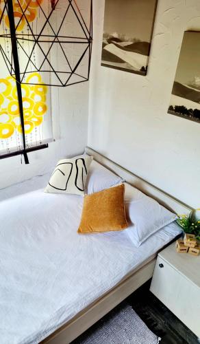 a bed with white sheets and a pillow on it at Kuća za odmor Malia sa Spa Hot Tub Jacuzzijem - Nice and Cozy - Free tickets to all City attractions in Ðurđevac
