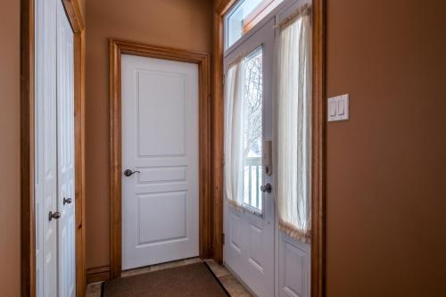 a hallway with a white door and a window at Aiglon by Rendez-Vous Mont-Tremblant in Mont-Tremblant